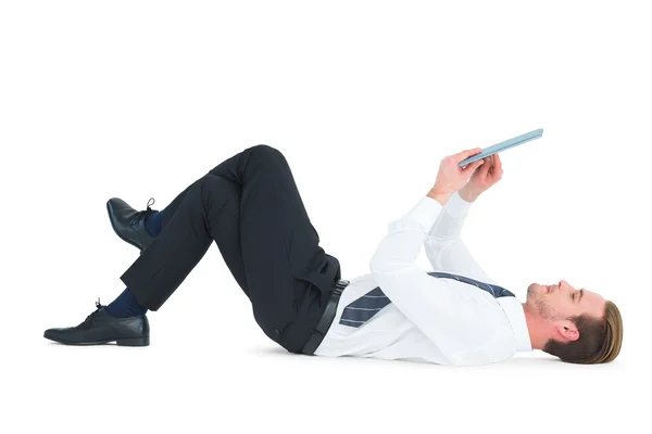 Businessman lying and using tablet — Stock Photo, Image