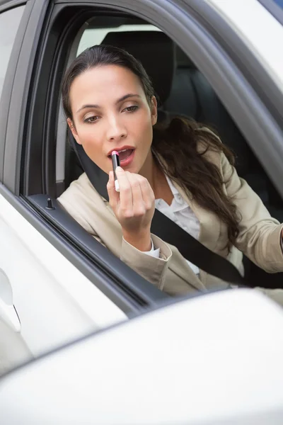 Bastante mujer de negocios usando el espejo del ala para poner en lápiz labial — Foto de Stock