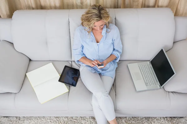 Blondine auf Couch mit Smartphone — Stockfoto