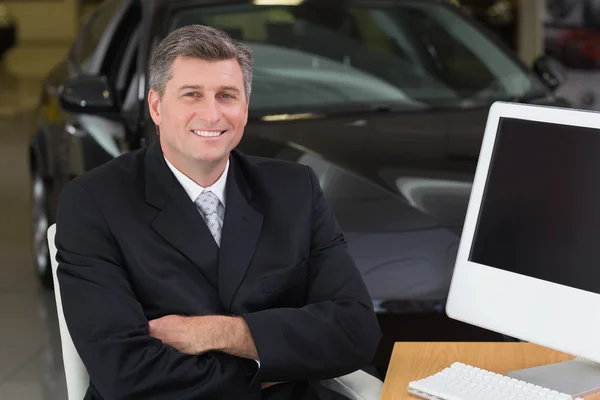 Hombre de negocios sonriente sentado en el escritorio — Foto de Stock