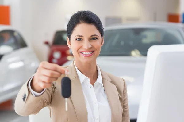 Vendedora sorrindo dando chave do carro do cliente — Fotografia de Stock