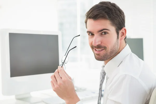 Empresário feliz segurando seus óculos — Fotografia de Stock
