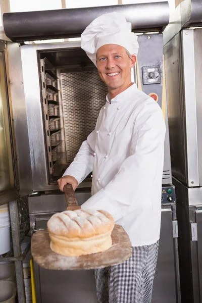 Happy baker taking out fresh loaf — Stock Photo, Image