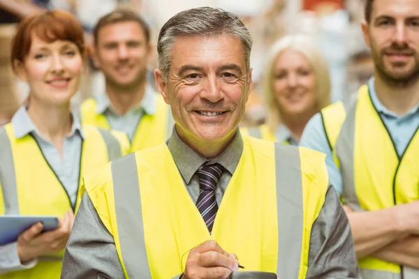 Warehouse team with arms crossed wearing yellow vest — Stock Photo, Image