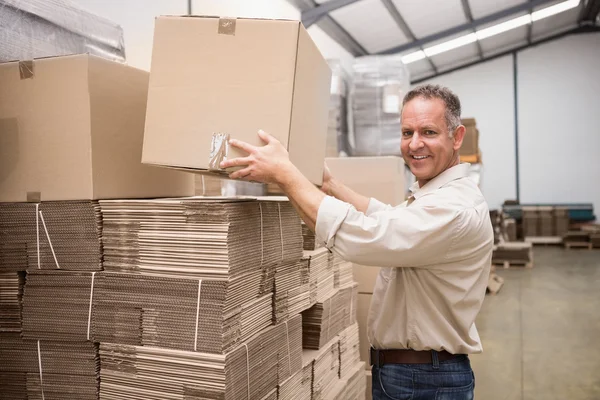 Sorrindo trabalhador armazém levando caixa — Fotografia de Stock