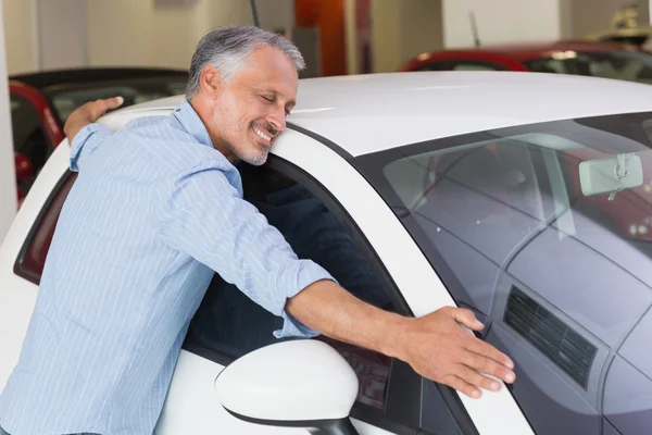 Χαμογελαστός άνθρωπος που αγκαλιάζει ένα λευκό αυτοκίνητο — Φωτογραφία Αρχείου