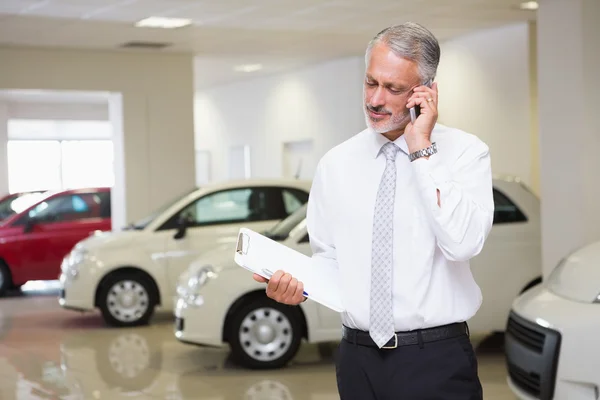 Empresário sorridente no telefone segurando prancheta — Fotografia de Stock