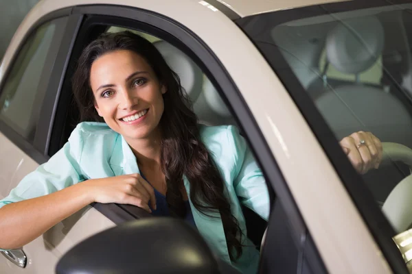 Усміхнена жінка сидить за кермом своєї нової машини — стокове фото