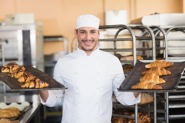 Smiling baker holding trays of croissants — Stock Photo, Image