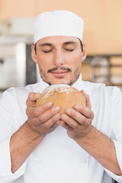 Baker smelling a freshly baked loaf — Stock Photo, Image