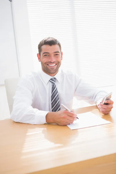 Homme d'affaires souriant écrivant à son bureau — Photo