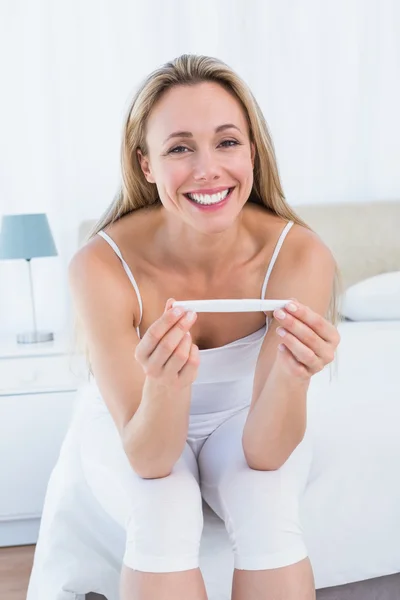 Smiling woman holding pregnancy test — Stock Photo, Image