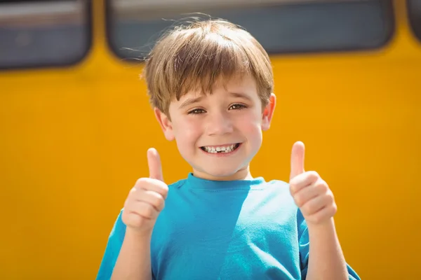Симпатичный ученик улыбается в камеру возле школьного автобуса — стоковое фото