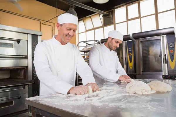 Bakkers kneden van deeg aan balie — Stockfoto