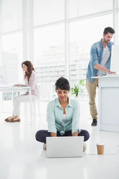 Forretningsdame som sitter på gulvet med bærbar PC – stockfoto