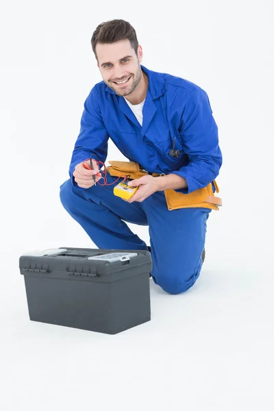 Happy repairman kneeling by toolbox — Stock Photo, Image