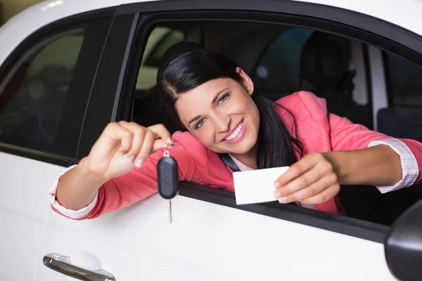 Leende kvinna med bilnyckel och visitkort — Stockfoto