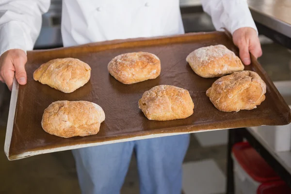 Baker showing tray with bread — Stock Photo, Image