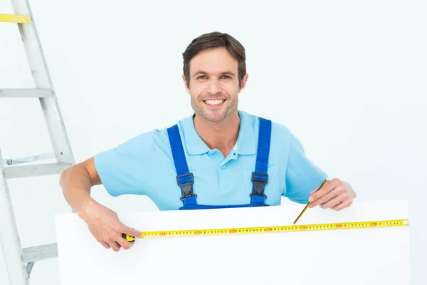 Carpintero midiendo tablero de factura en blanco — Foto de Stock