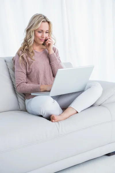 Loira sentada no sofá usando laptop — Fotografia de Stock