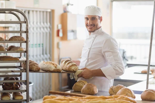 Smiling baker holding tray of bread — Stock Photo, Image