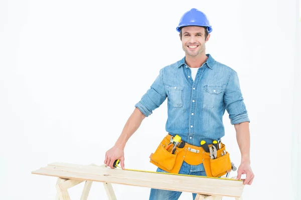 Male carpenter measuring wooden plank — Stock Photo, Image