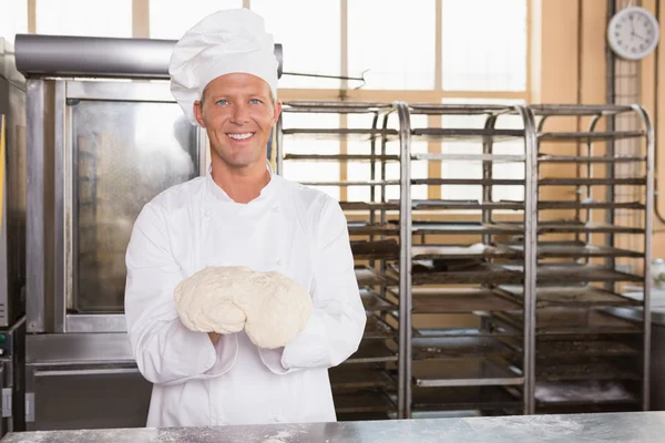 Panadero sonriente sosteniendo masa cruda — Foto de Stock