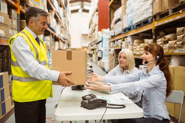 Manager indossa giubbotto giallo dando scatola al suo collega — Foto Stock