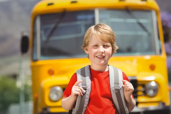 Lindo alumno sonriendo a la cámara por el autobús escolar — Foto de Stock