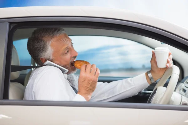 Mann trinkt Kaffee und isst Donut am Telefon — Stockfoto