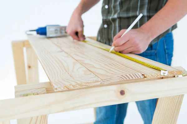 Carpenter marking with measure tape on plank — Stock Photo, Image