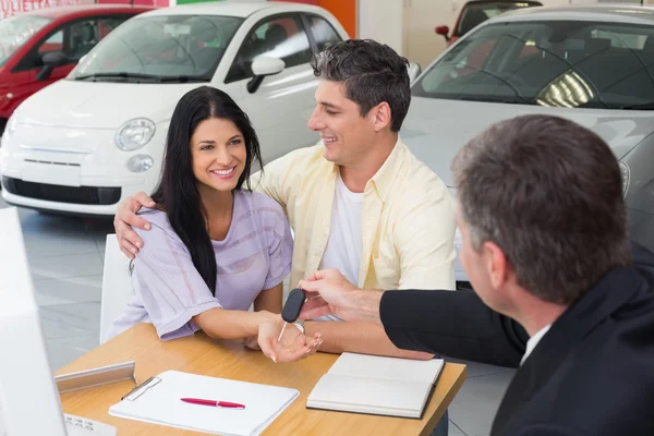 Salesman giving key to smiling couple — Stock Photo, Image