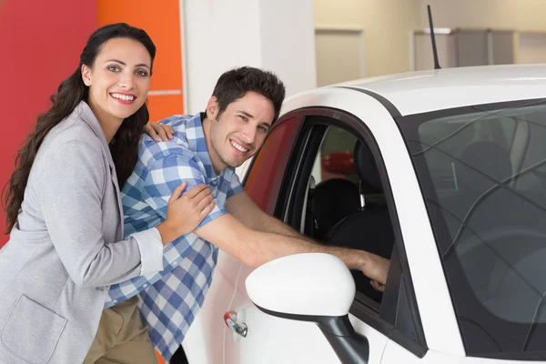 Smiling couple looking inside a car — Stock Photo, Image