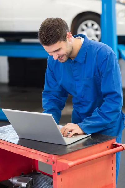 Lachende mechanic met behulp van zijn laptop — Stockfoto