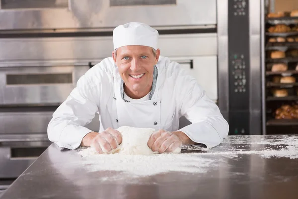 Smiling baker kneading dough on counter — Stock Photo, Image