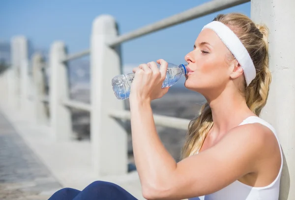 Ajuste rubia sentado en el muelle de agua potable — Foto de Stock