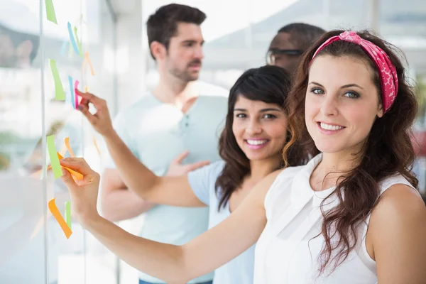Smiling coworkers pointing sticky notes — Stock Photo, Image