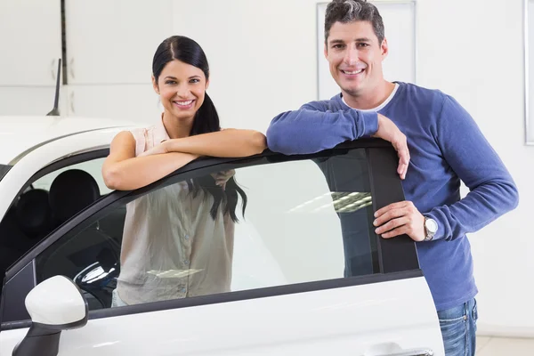 Smiling couple leaning on car — Stock Photo, Image