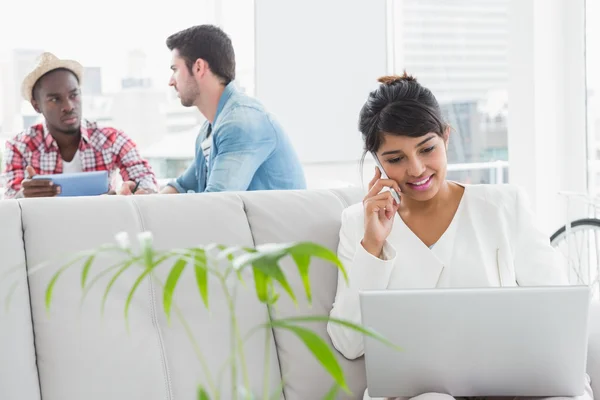 Zakenvrouw bellen en met behulp van laptop op Bank — Stockfoto