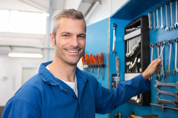 Mechanic taking a tool from wall — Stock Photo, Image