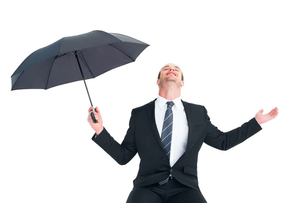 Businessman sheltering under black umbrella testing — Stock Photo, Image