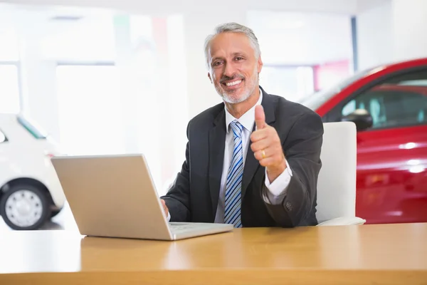 Empresário sorrindo dando polegares para cima usando seu laptop — Fotografia de Stock