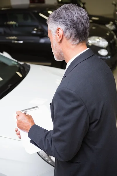 Seriöser Geschäftsmann schreibt auf Klemmbrett — Stockfoto