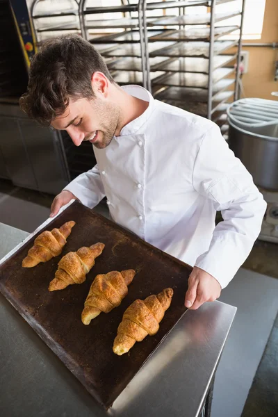 Baker showing croissants on baking tray — Stock Photo, Image