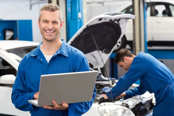 Meccanico sorridente utilizzando un computer portatile — Foto Stock