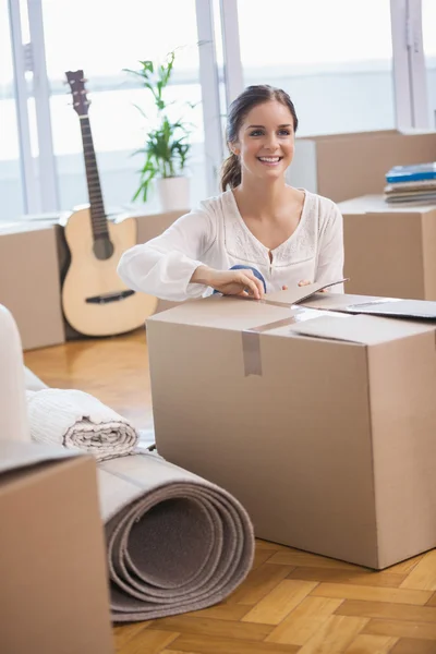 Smiling woman unpacking cardboard boxes — Stock Photo, Image