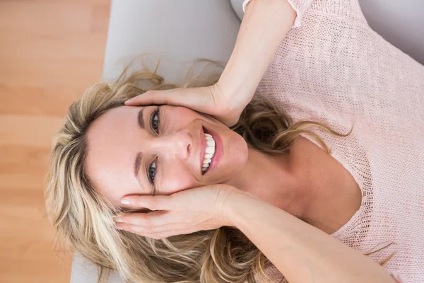 Blonde on couch with hand on head — Stock Photo, Image