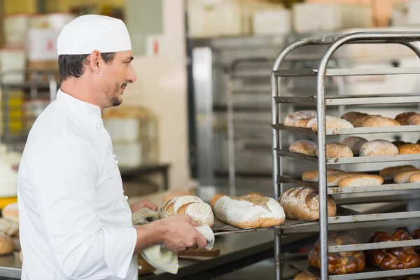 Smiling baker holding tray of bread — Stock Photo, Image