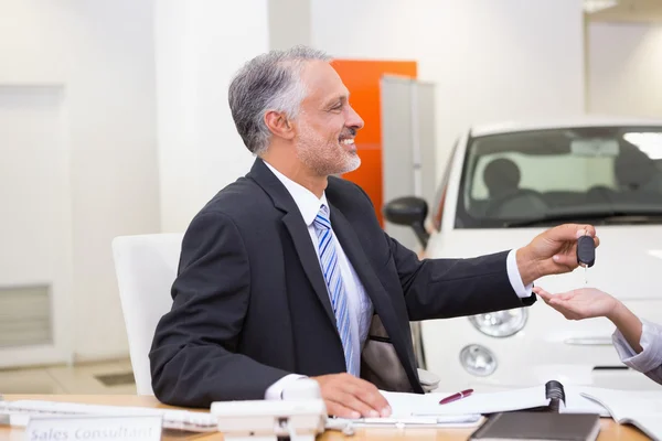 微笑推销员给客户的车钥匙 — 图库照片