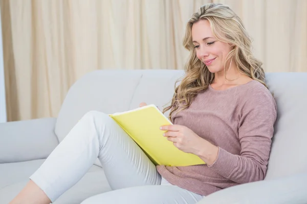 Blonde on couch reading notebook — Stock Photo, Image